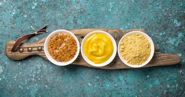 3 different types of mustard on wood board