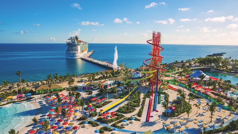 Aerial view of Perfect Day at CocoCay with royal caribbean water slides at Daredevil’s Tower, sandy beaches, and Navigator of the Seas docked nearby