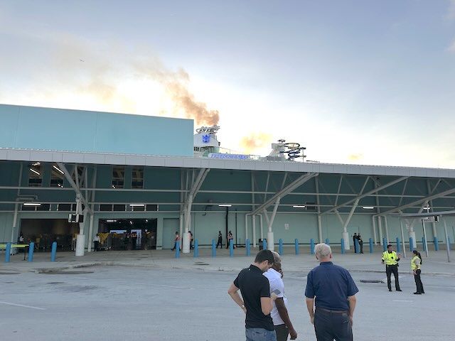 Why I Set My Alarm on Disembarkation Day for Royal Caribbean picture of the ship in the background and people standing on disembarkation day
