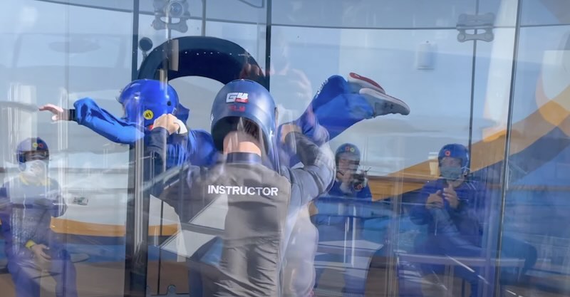 Young child flying in the skydiving simulator on rccl ship ifly with an instructor