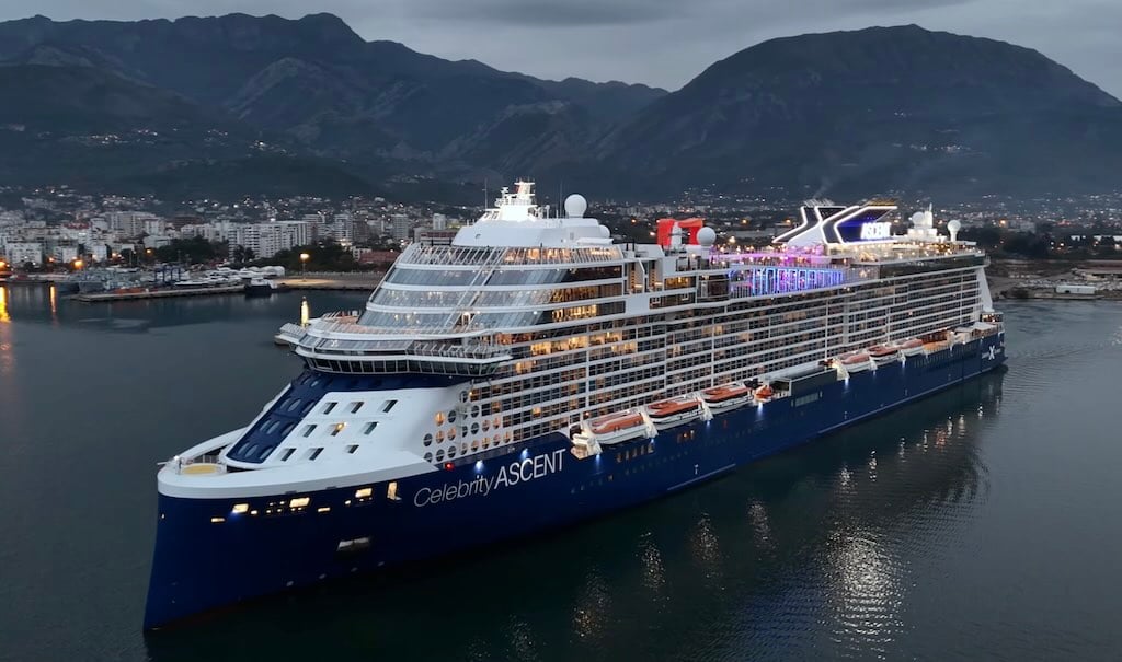 Celebrity Ascent cruise ship sailing near a coastal city at dusk