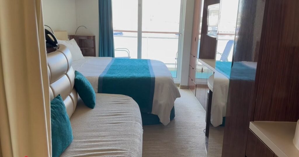 Norwegian cruise balcony stateroom showing bed, sofa, storage and balcony doors